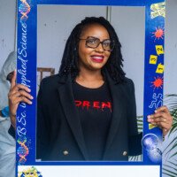 Woman posing by the Forensic Chemistry booth at UTECH Open House day 1.
Location: Alfred Sangster Auditorium
Date: October 15, 2025